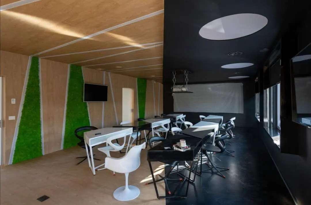 Spațiu cu perete verde vegetal, tavan negru, mese rotunde — mobilier comercial la comandă Fine Cut Furniture